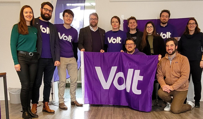Members of Volt standing together holding up a Volt flag