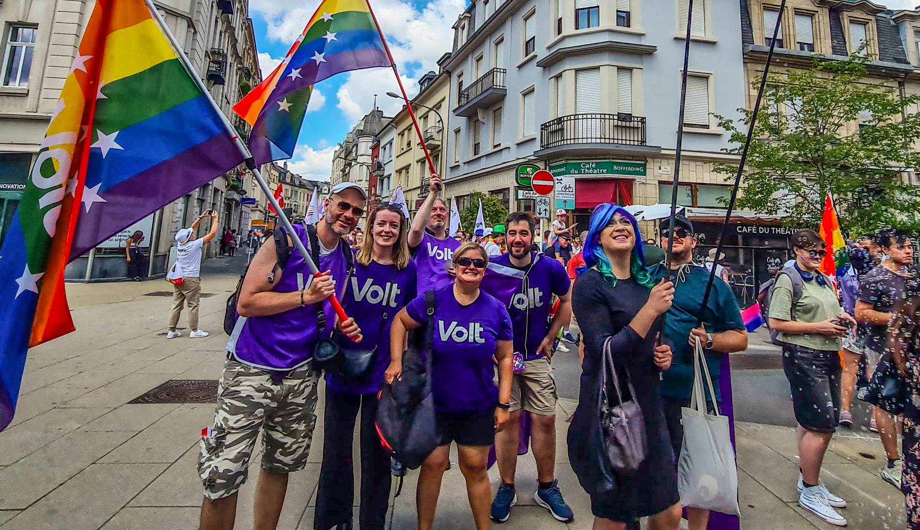 Volters wearing purple and waving rainbow flags at the Equality March 2025