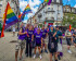 Volters wearing purple and waving rainbow flags at the Equality March 2025