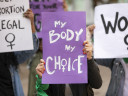 Women holding posters which read