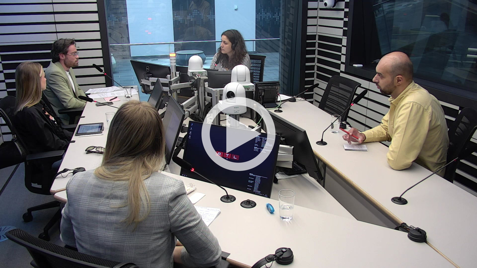 People sitting in the RTL studio around tables and monitors.